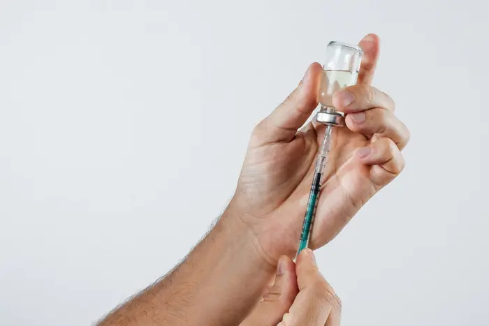 A person holding a syringe with a needle, administering botox treatment for hyperhidrosis.